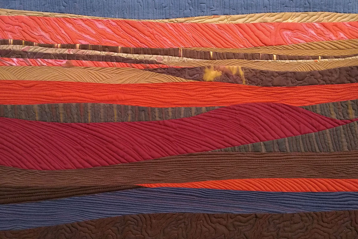 Red, orange, brown, and blue layered fiber art by Julia Crocetto