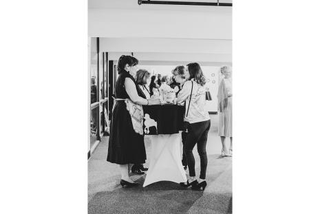Black and white photo of guests mingling around a high top table